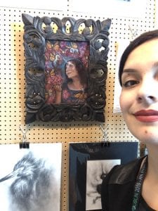 Lauren standing in front of a piece of art in an ornate frame